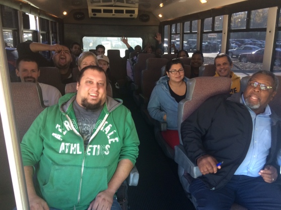 A group of men and women sit on a bus.