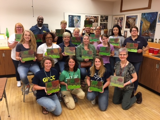 The School of Workforce Development APSS members show off their paintings after a group retreat.
